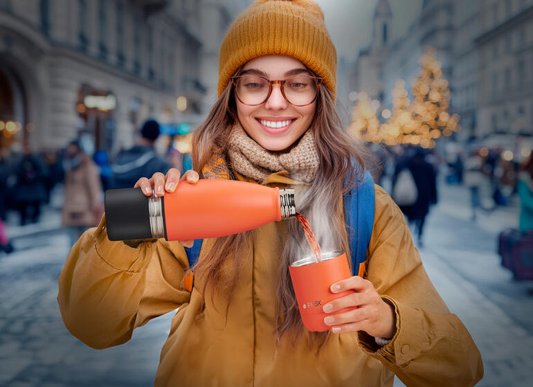De beker is gewoon geïntegreerd in de bodem van de fles ... Vrouw op straat giet uit een isolerende fles in een beker.