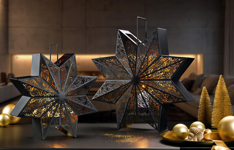 Twee decoratieve lantaarns in stervorm op een tafel met gouden kerstballen.