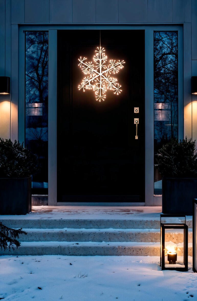 Verlichte LED-sneeuwvlok voor buiten, hangend voor een voordeur.