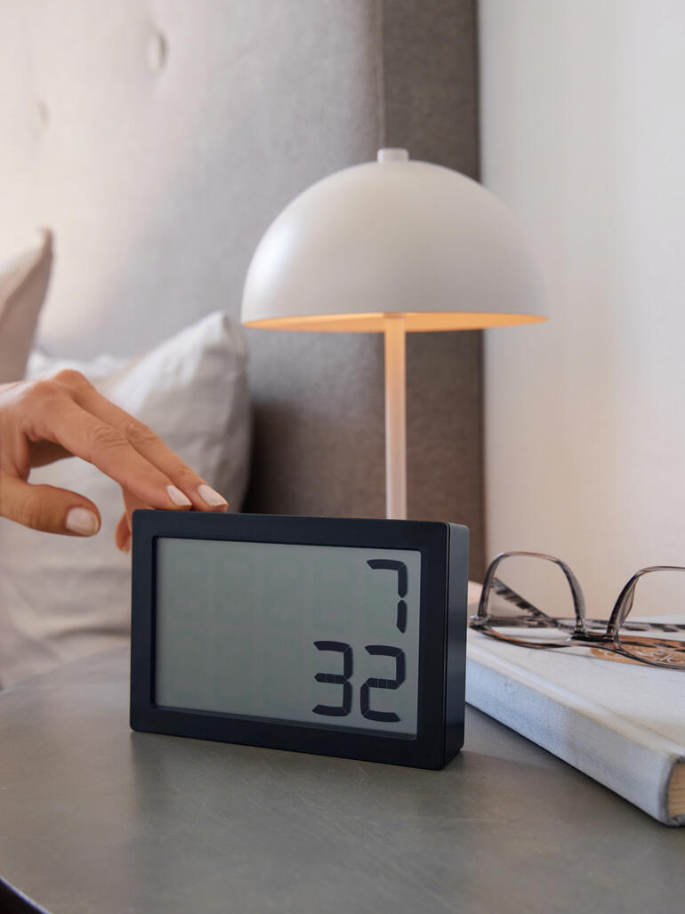 Hand raakt de digitale tafelklok 