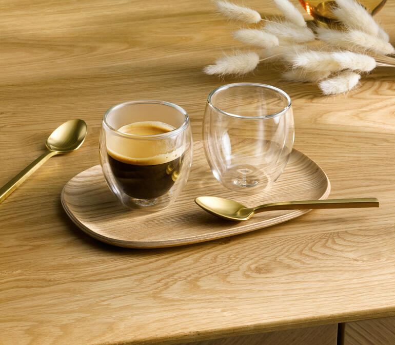Twee premium thermoglasen op een houten bord, een bevat espresso.