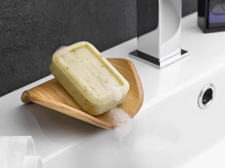 Houten zeepbakje met zeep, op een badkamer wastafel