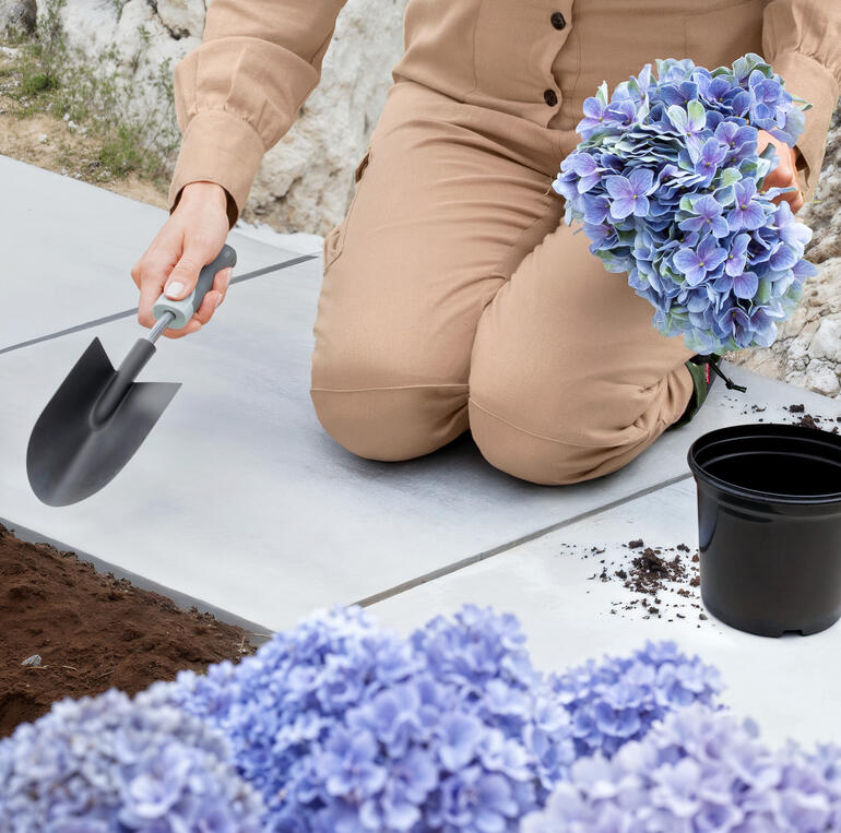 Verstevigde knieën incl. beschermkussen voor comfortabel werken. Detailweergave van bloemen in de handen van een vrouw.