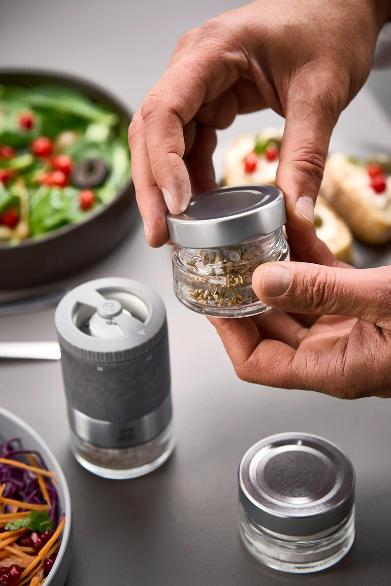 Peugeot Zirkonia-zoutmolenset, handen houden een kruidenfles boven een saladeschaal