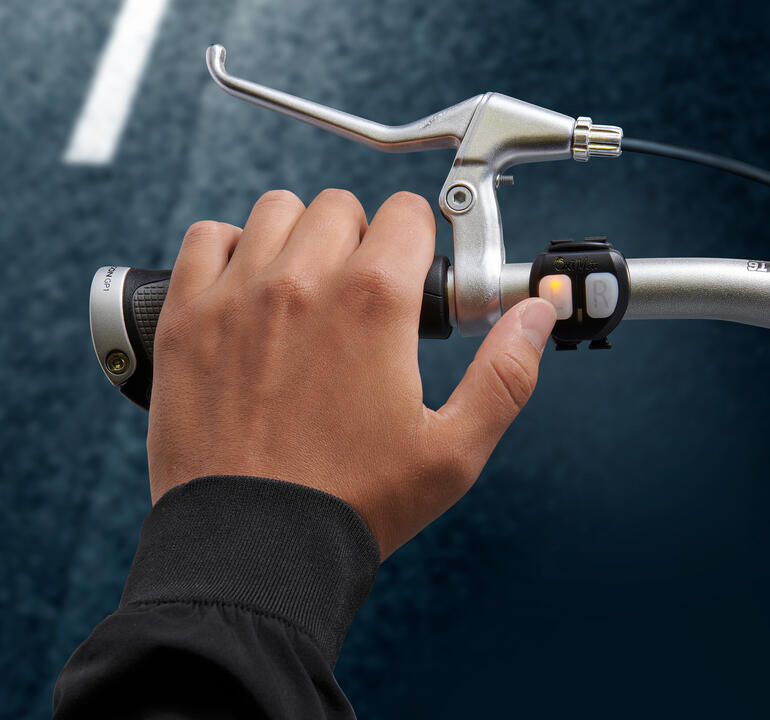 Fietshelm met lichtsignalen Hand drukt de schakelaar voor het lichtsignaal op het fiets stuur