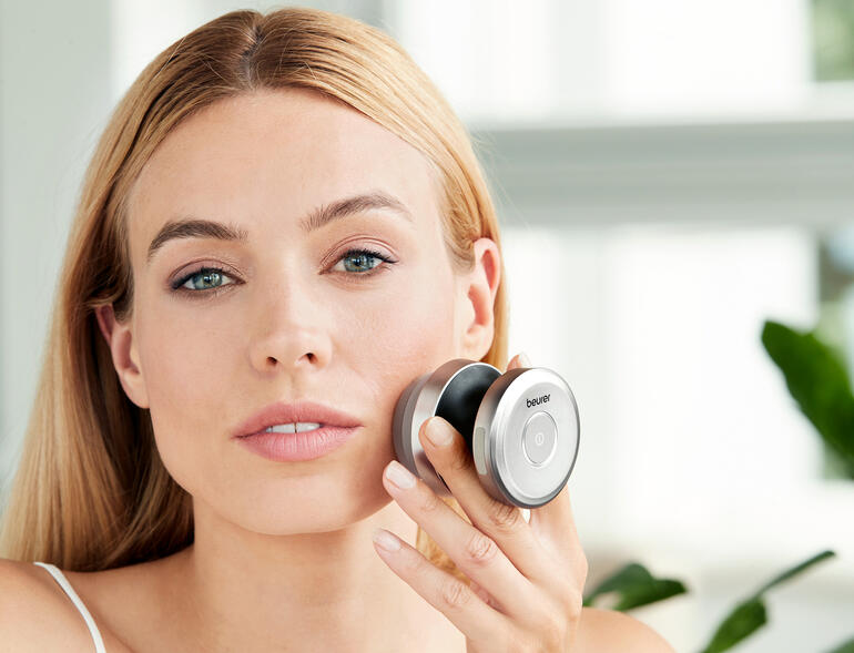 Dual gezichtborstel in gebruik, vrouw houdt borstel tegen haar gezicht.