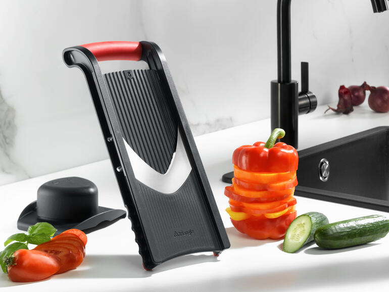 Groenteschaaf met resthouder, gepresenteerd naast verse groenten.