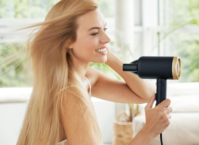 Compacte reisblowdryer in gebruik, vrouw die haar haar droogt.