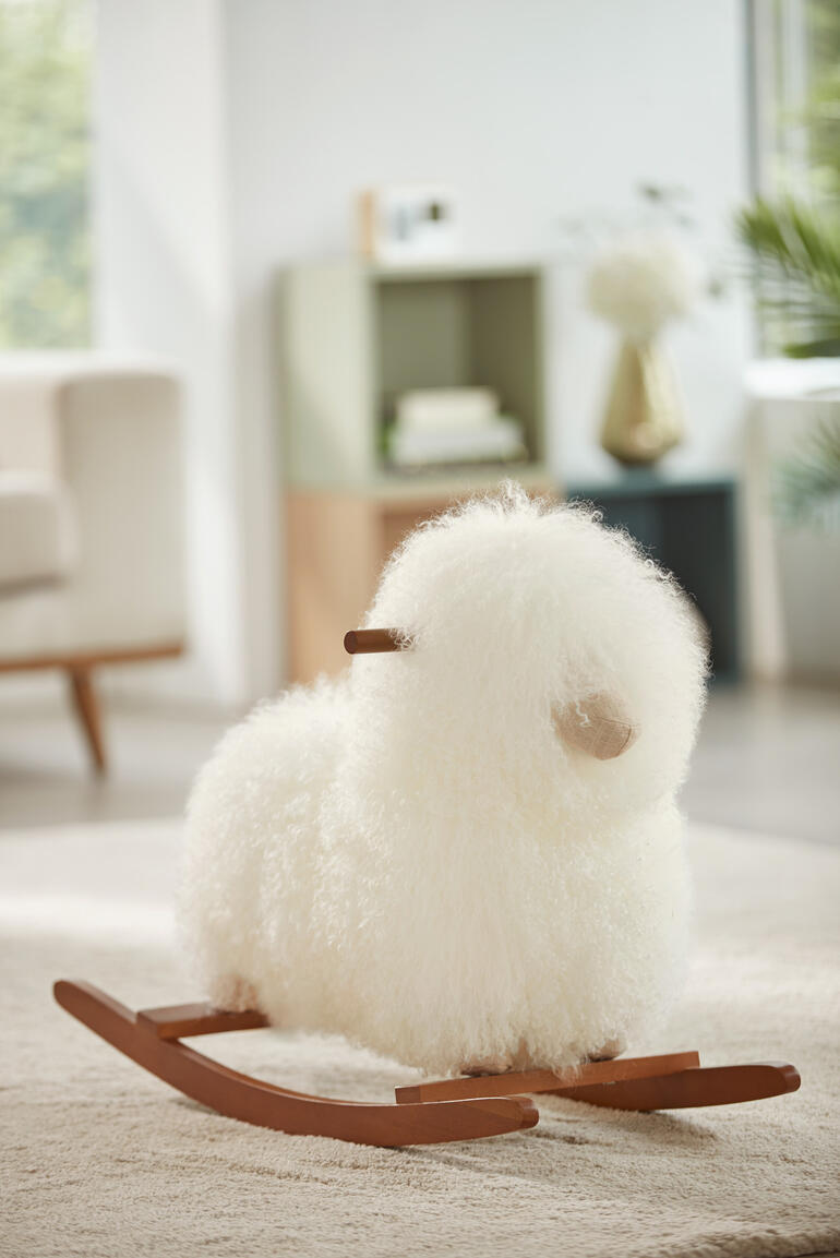 Echt schapenvacht schommel schaap in het wit op een vloerkleed.