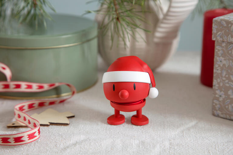 Hoptimist sneeuwman met een rode kersthoed op een feestelijke tafel.