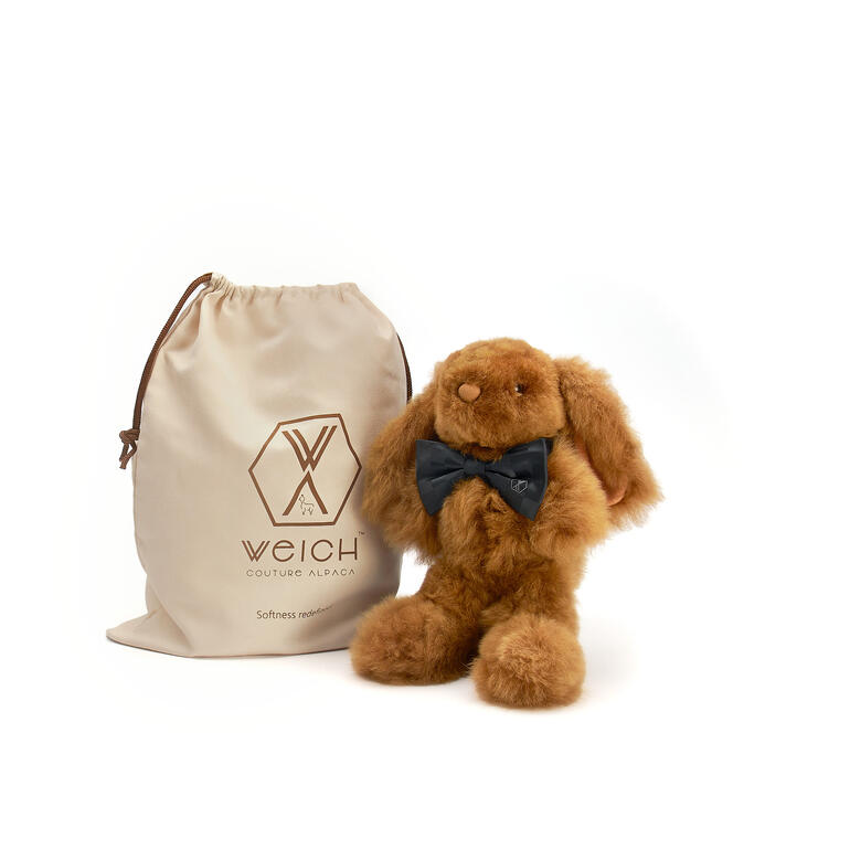 Verkrijgbaar in champagnekleur of goudbruin, inclusief opbergtas met trekkoord. Kleine champagne kleurige alpaca-conijn naast een stoffen zak.