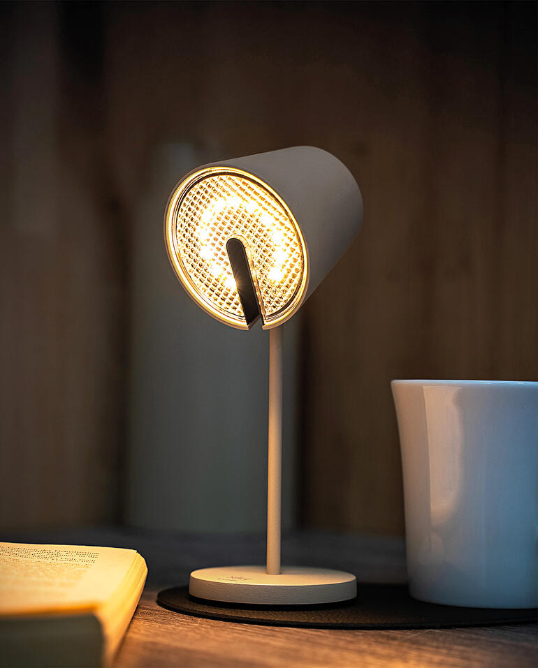 Zwarte magnetische lamp met helder licht, staat op een tafel naast een mok.