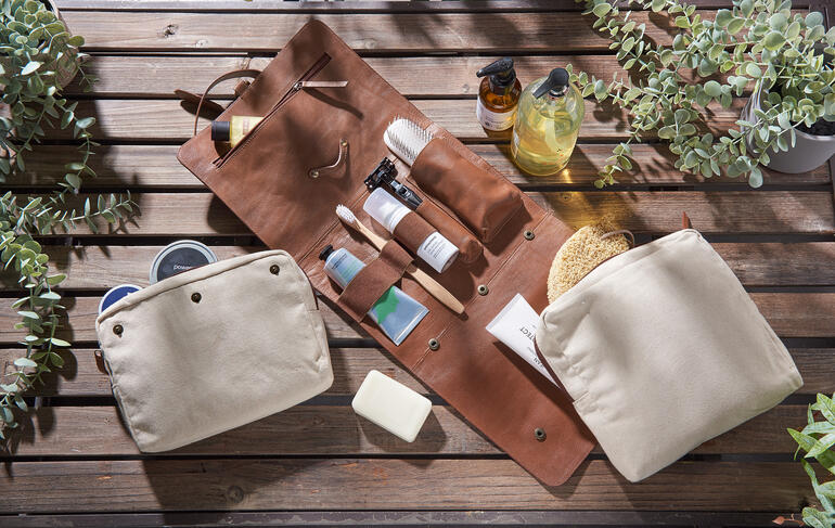 Buffellederen toilettas met verschillende verzorgingsproducten op een tafel.