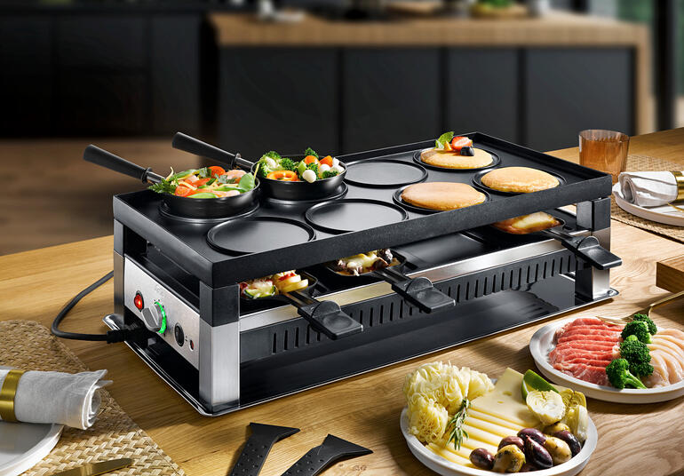 Solis raclette- en fun-koken 5-in-1 apparaat met groenten en vlees op de tafel.