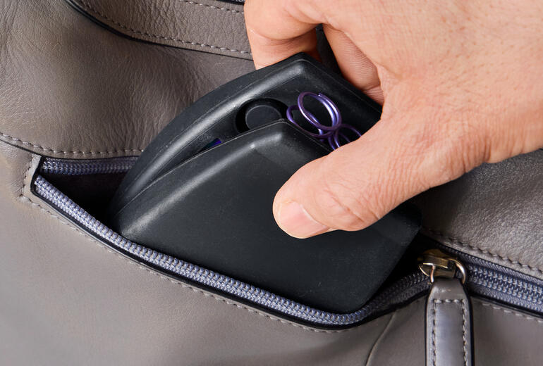 Ideaal om mee te nemen, bijvoorbeeld voor de training in het park of op reis. Hand pakt een compacte bovenlichaamstrainer uit een tas