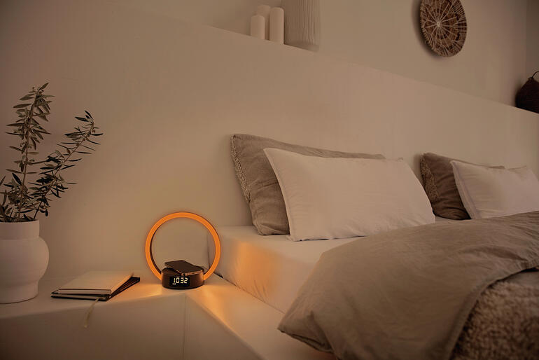 Wecker met ronde, verlichte display op een nachtkastje.