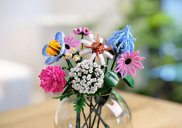 Bloemstuk van bouwstenen in rosé- en lila tinten in een vaas.