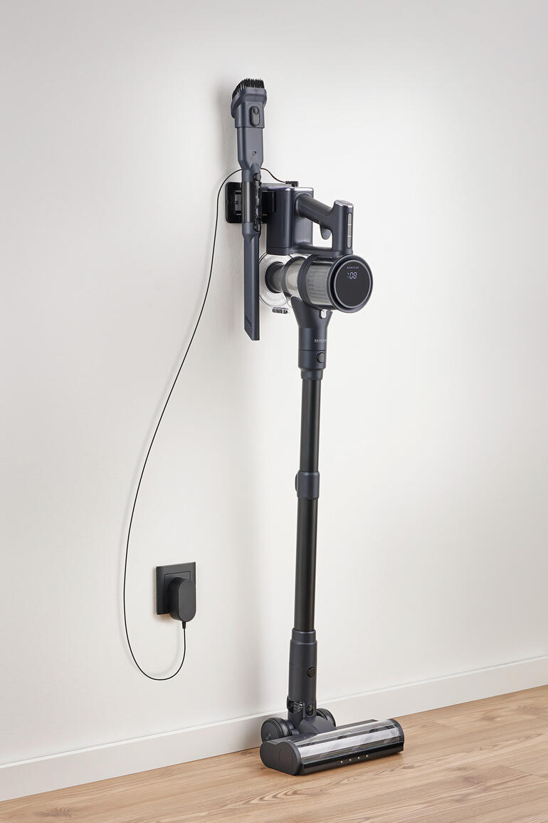 Accu-stofzuiger aan de muur gemonteerd, met oplader.
