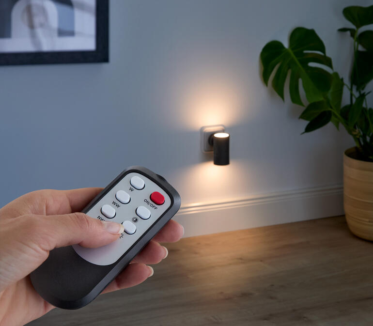 Afstandsbediening voor dimbare wandlamp wordt vastgehouden.