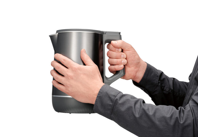 Gebruiker houdt de dubbele waterkoker met 3D-verwarmingssysteem vast.