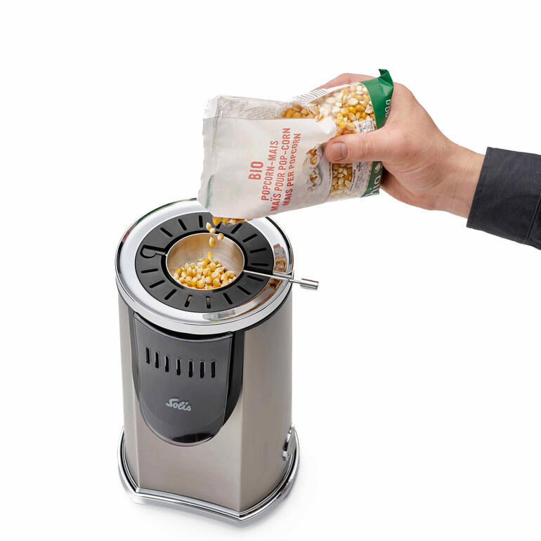 Persoon giet popcorn in de Solis popcornmaker.