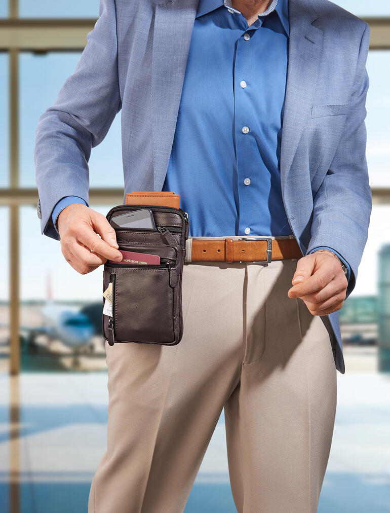 Man met een kleurgecoördineerde buffelleer heuptas die hij aan zijn riem vasthoudt.