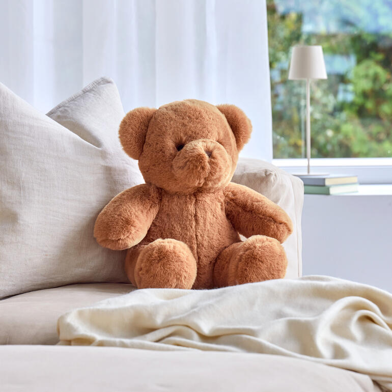 Bruine teddybeer op een comfortabele bank, klaar om te knuffelen.