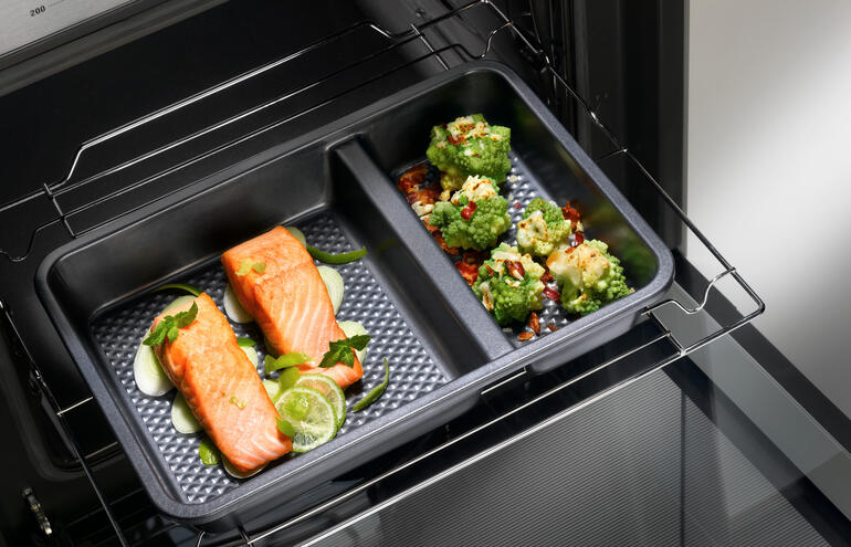 Twee-delige ovenschaal met zalm en groenten in de oven