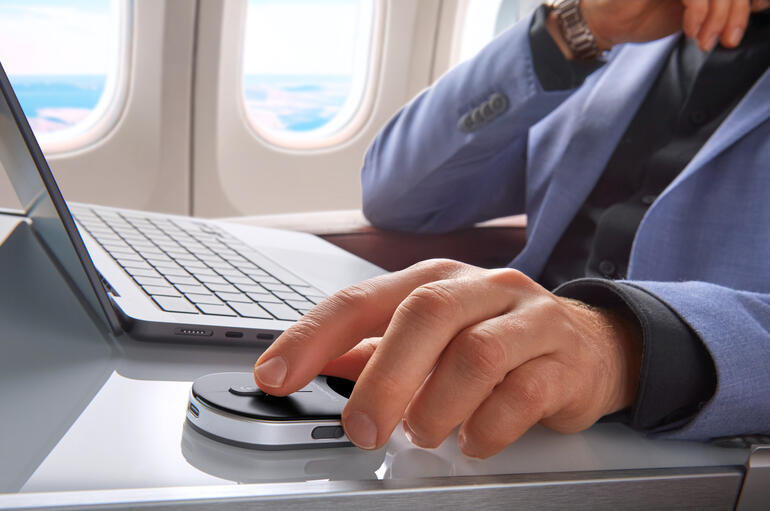 Man in een vliegtuig gebruikt een mobiele mini-muis op een tafel.