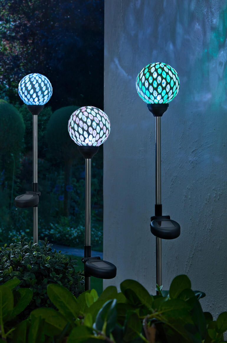Drie solar tuinstekers met kleurrijke mozaïek lampen in de tuin.