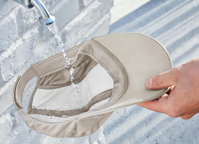 Beige koelcap wordt met de hand onder water gehouden terwijl het water eruit stroomt