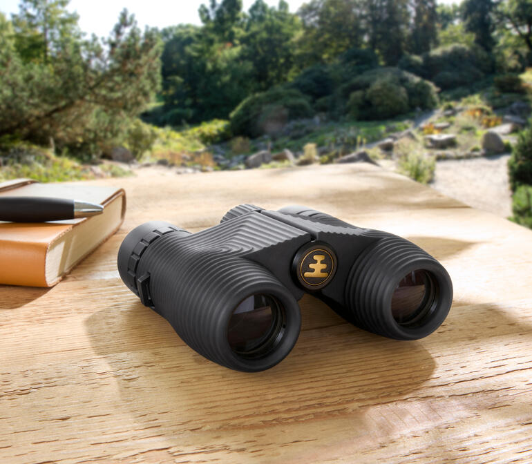 Compacte verrekijker op een houten tafel in de natuur.