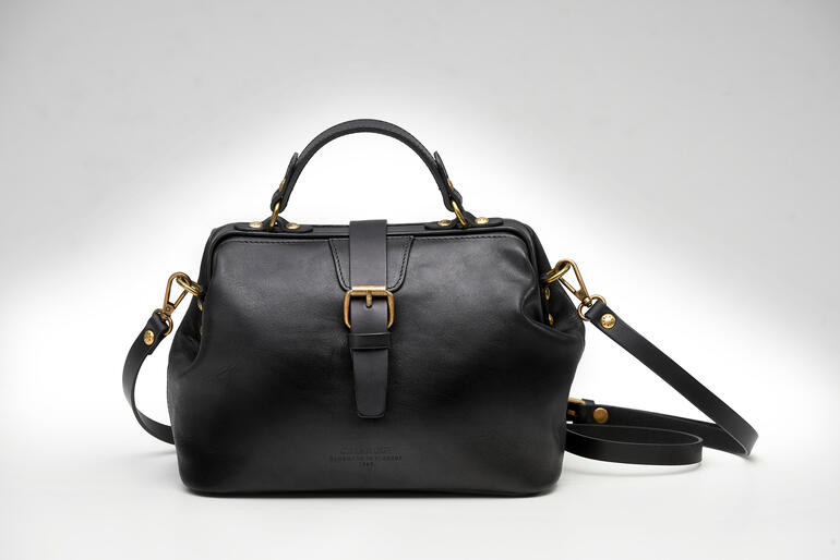 Zwarte damestas met gestructureerd leer op een witte achtergrond.