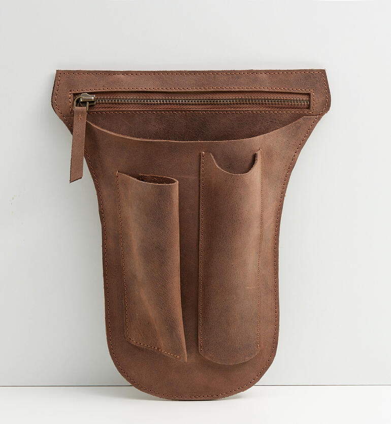 Bruine gereedschapsgordeltas van buffelleer met meerdere zakken op een grijze achtergrond.