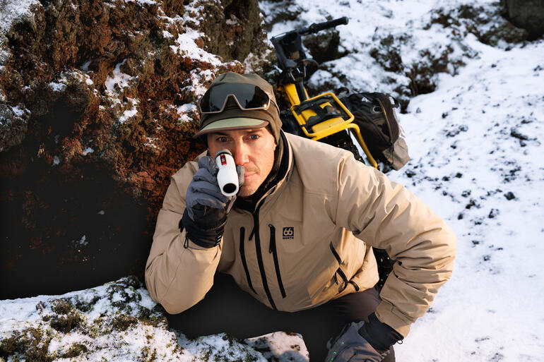 Man kijkt met een monoculaire in de bergen tijdens de sneeuw.