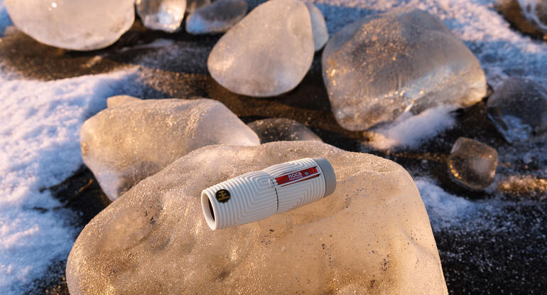 Nocs Provisions ZeroTube 10x25 monoculaire op een ijsblok in een winterlandschap.