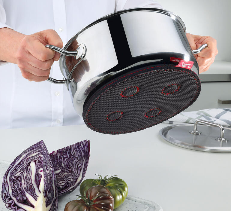 Hand die een magnetische onderzetter onder een kookpan houdt.