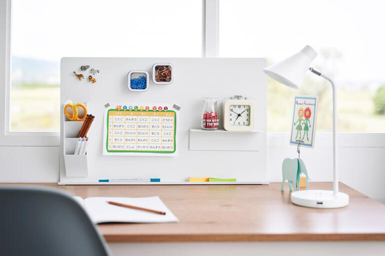 Wit magnetisch prikbord met kantoorbenodigdheden op een bureau.