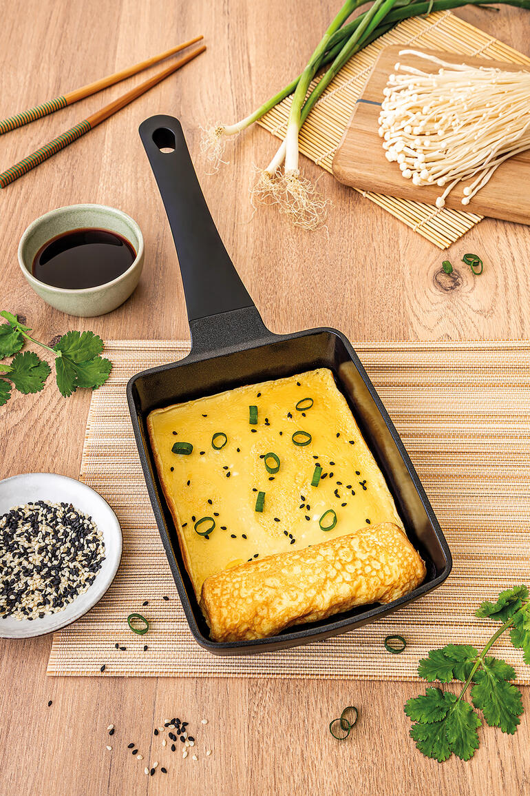 Tamagoyaki-pan met omelet, gepresenteerd op een houten plank.