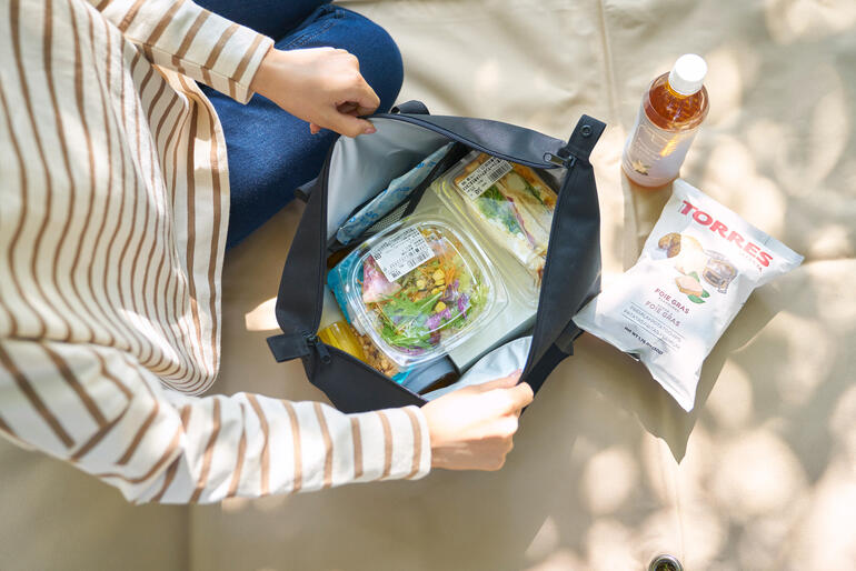 Vrouw opent een Vario-koeltas en toont verse levensmiddelen van binnen.