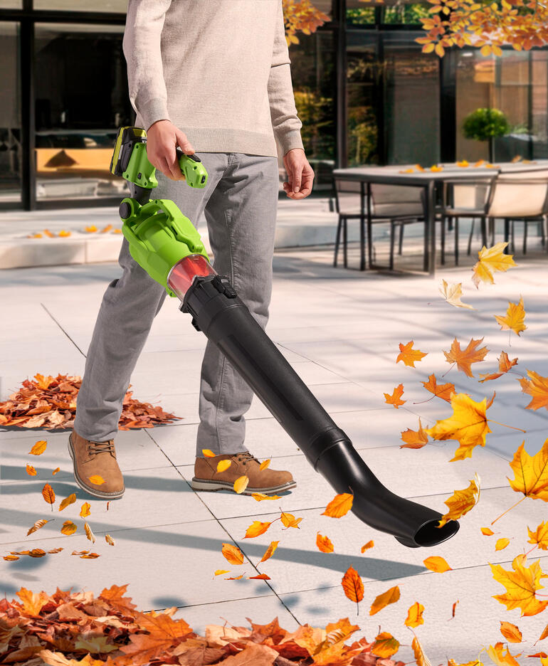 Man gebruikt draadloze telescoop bladblazer op het terras in de herfst.