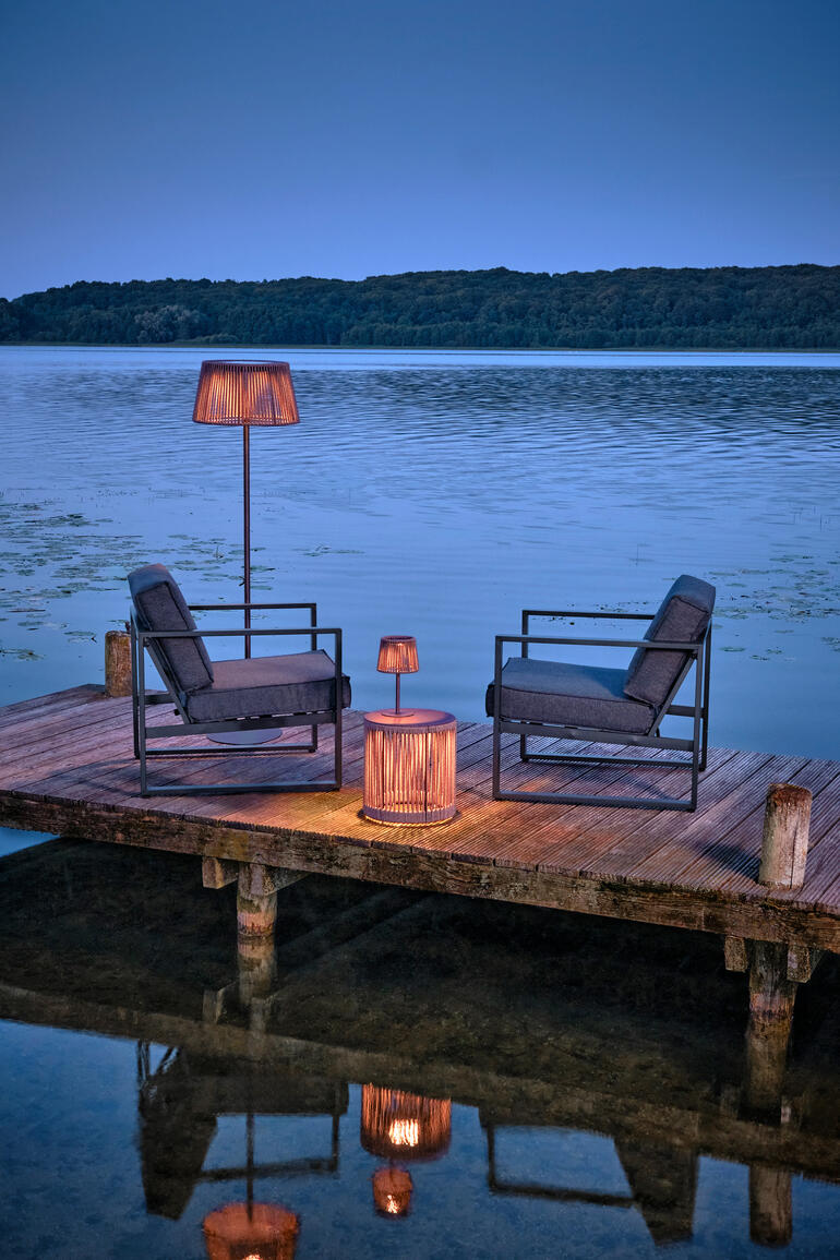 Buiten tafel met LED-verlichting aan water, omringd door stoelen.