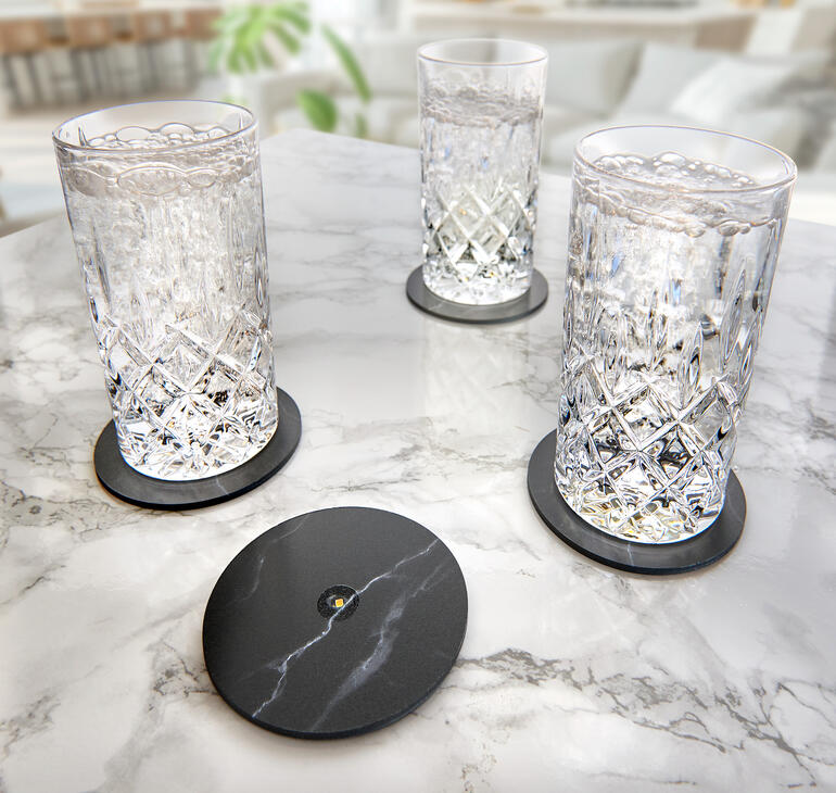 Drie glazen op een marmeren oppervlak met zwarte onderzetters voor een elegante drinkervaring.