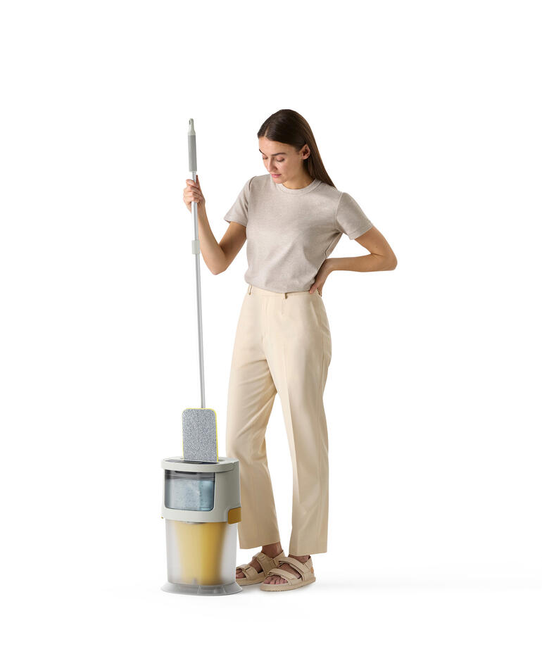 Vrouw houdt een vloerwisser boven de emmer in een moderne keuken.