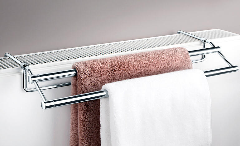 Handdoekdroger gemonteerd boven een radiator met handdoeken.