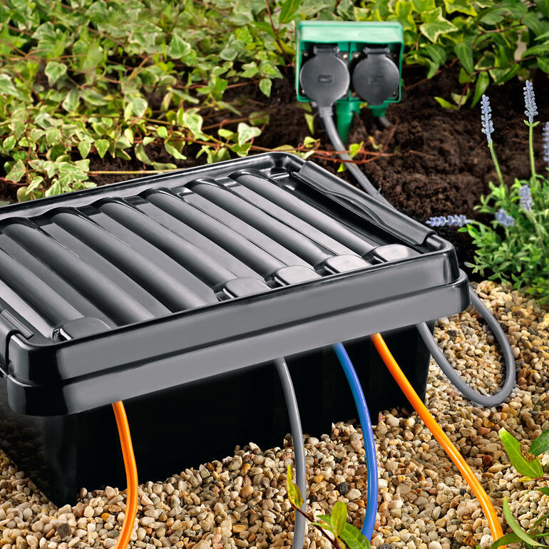 DRi®BOX met kabels op de grond omringd door planten.