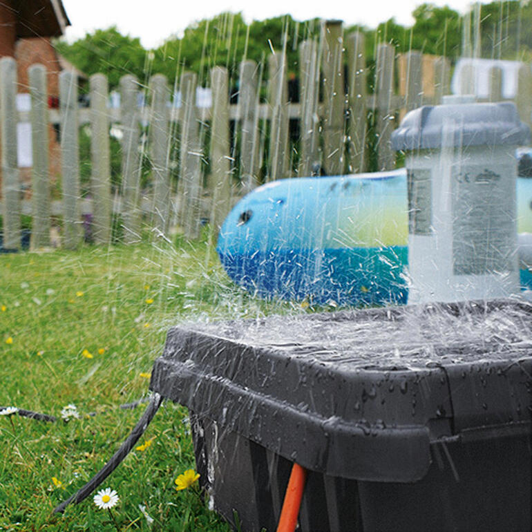 Met de hoge beschermingsklasse IP 55 is de DRi®BOX 100 % stof- en waterdicht. DRi®BOX wordt geraakt door spetters water op een gazon.