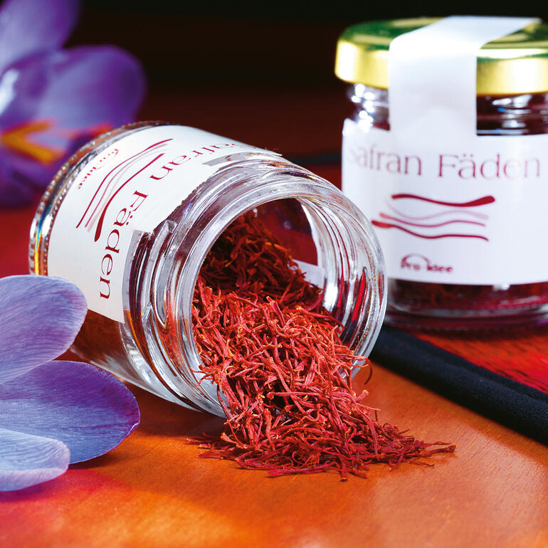 Iranese saffraandraadjes in een pot, omringd door bloeiende planten.