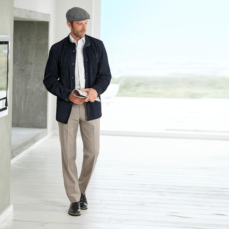 Man in een zwarte rendierkalfsleder hemdjack, staand in een moderne kamer met lichte kleuren.