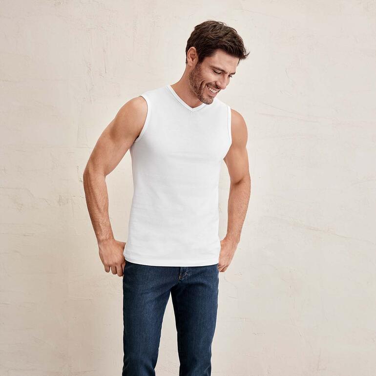 Man in mouwloos shirt, glimlachend en naar beneden kijkend